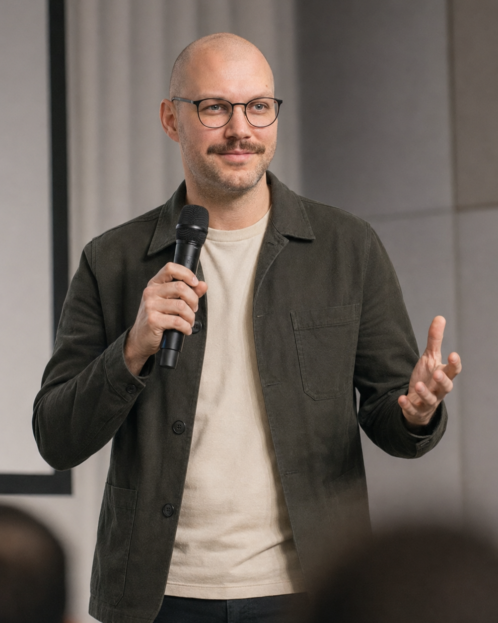 Simon Ehlebracht spricht mit Mikrofon auf einer Bühne